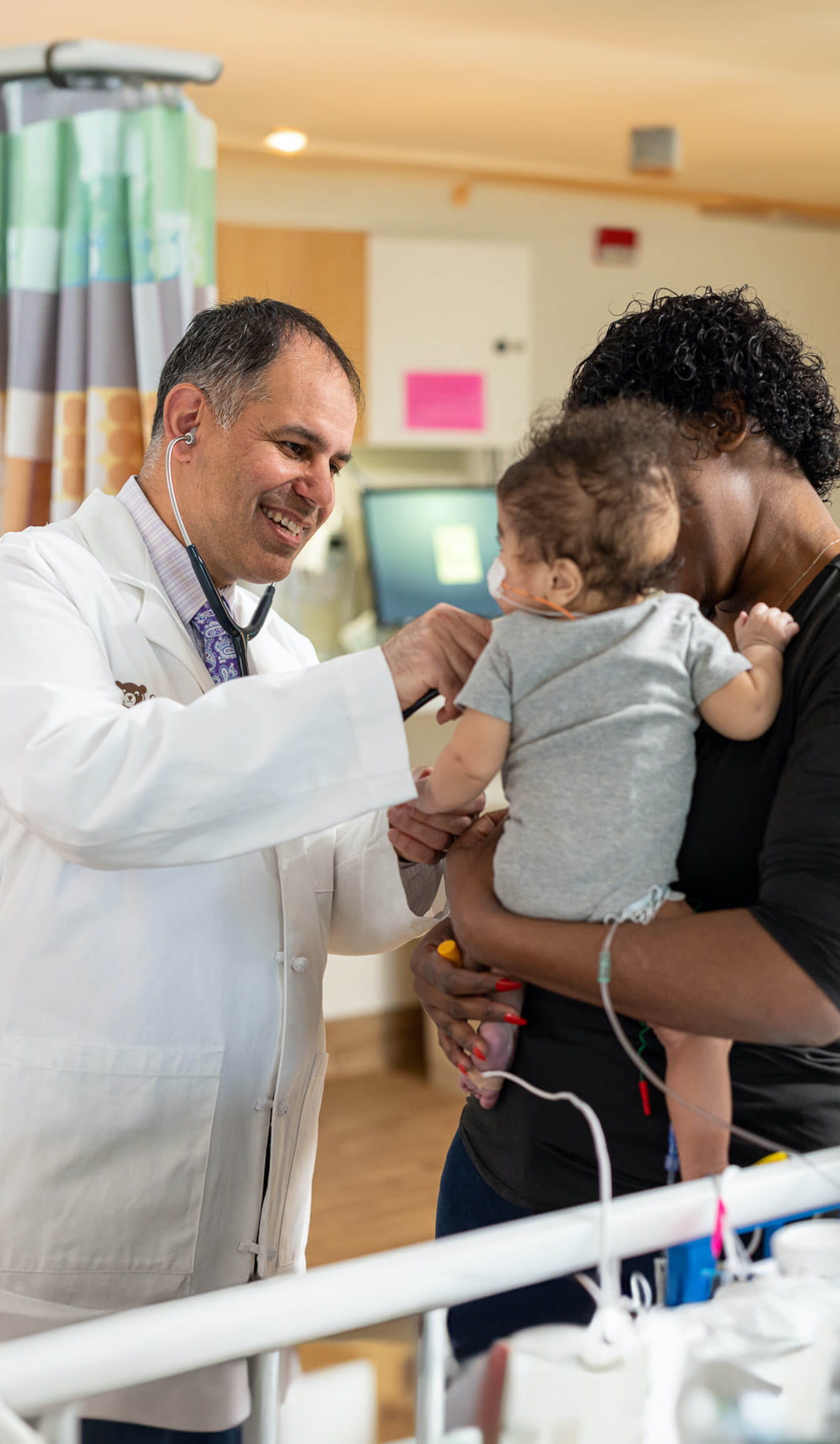 Doctor using stethoscope to check baby's heartbeat in parent's arms.